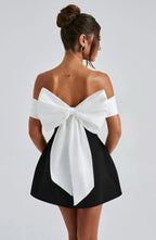 Women wearing Harrow amber off-shoulder mini dress with bow detail, perfect for romantic cocktail parties.